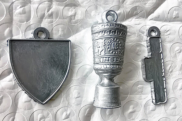 Drei ungefertigte Rohlinge des Pokal-Schlüsselanhängers 2025 – noch ohne Farbe, Druck oder Oberflächenveredelung.
