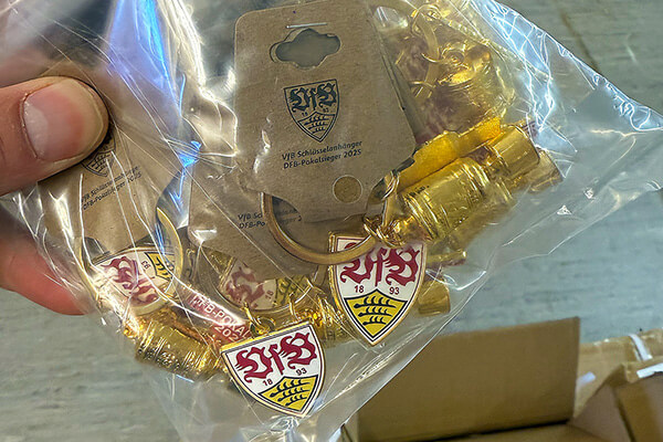 Detailansicht einer Verkaufsverpackung mit einem Pokal-Schlüsselanhänger 2025.